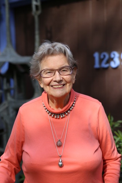 Priscilla Kapel at her desk holding a maitake mushroom